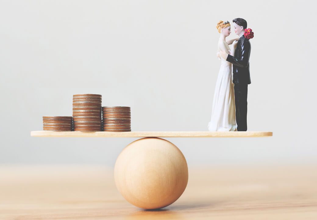 bonecos de noivos e moedas em uma balança de gastos para casamento