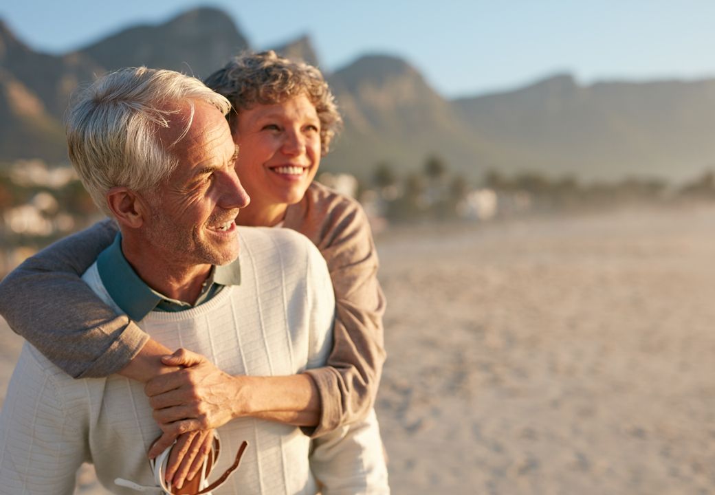 casal de meia idade na praia sorrindo aproveitando a vida